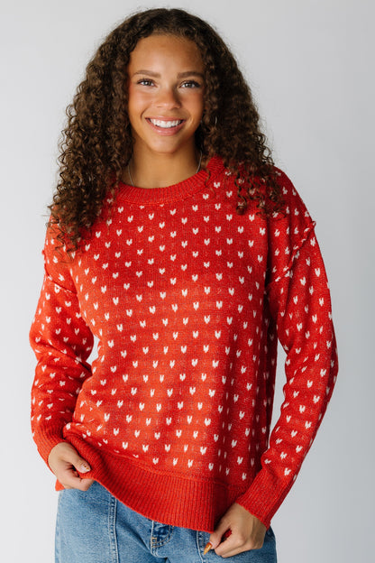 Woman wearing a modest long sleeve sweater with hearts, long sleeves and a crew neckline