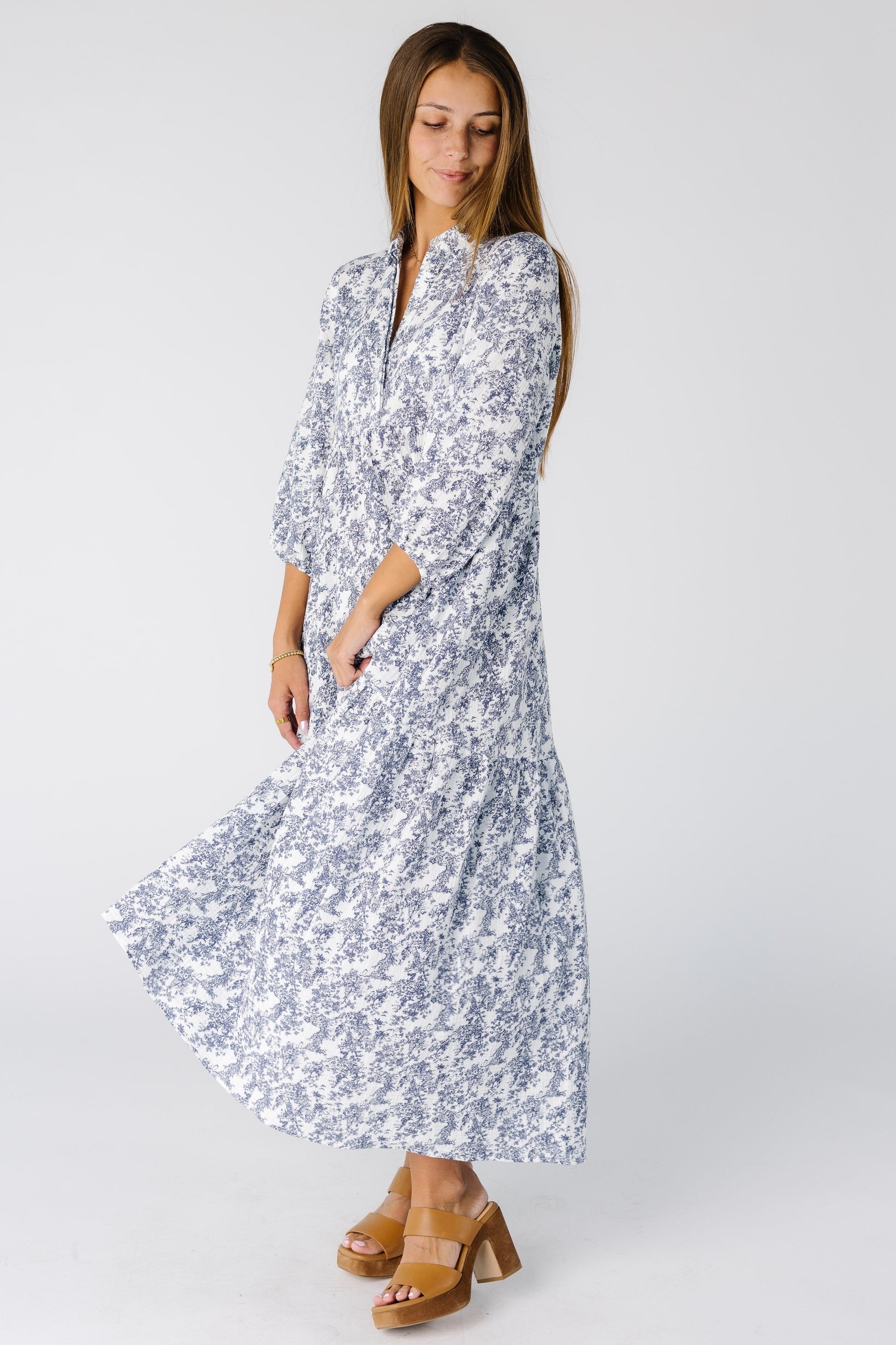 Woman wearing a modest white and blue loose fitting midi dress with 3/4 length sleeves and V-neckline