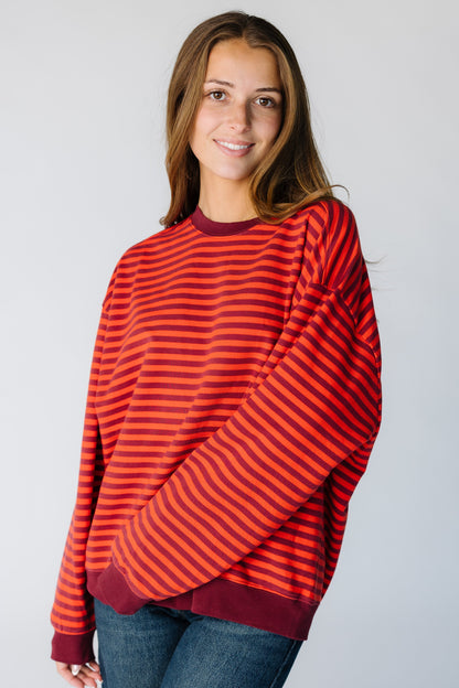 Woman wearing a very loose fitting sweatshirt in a burgundy stripe