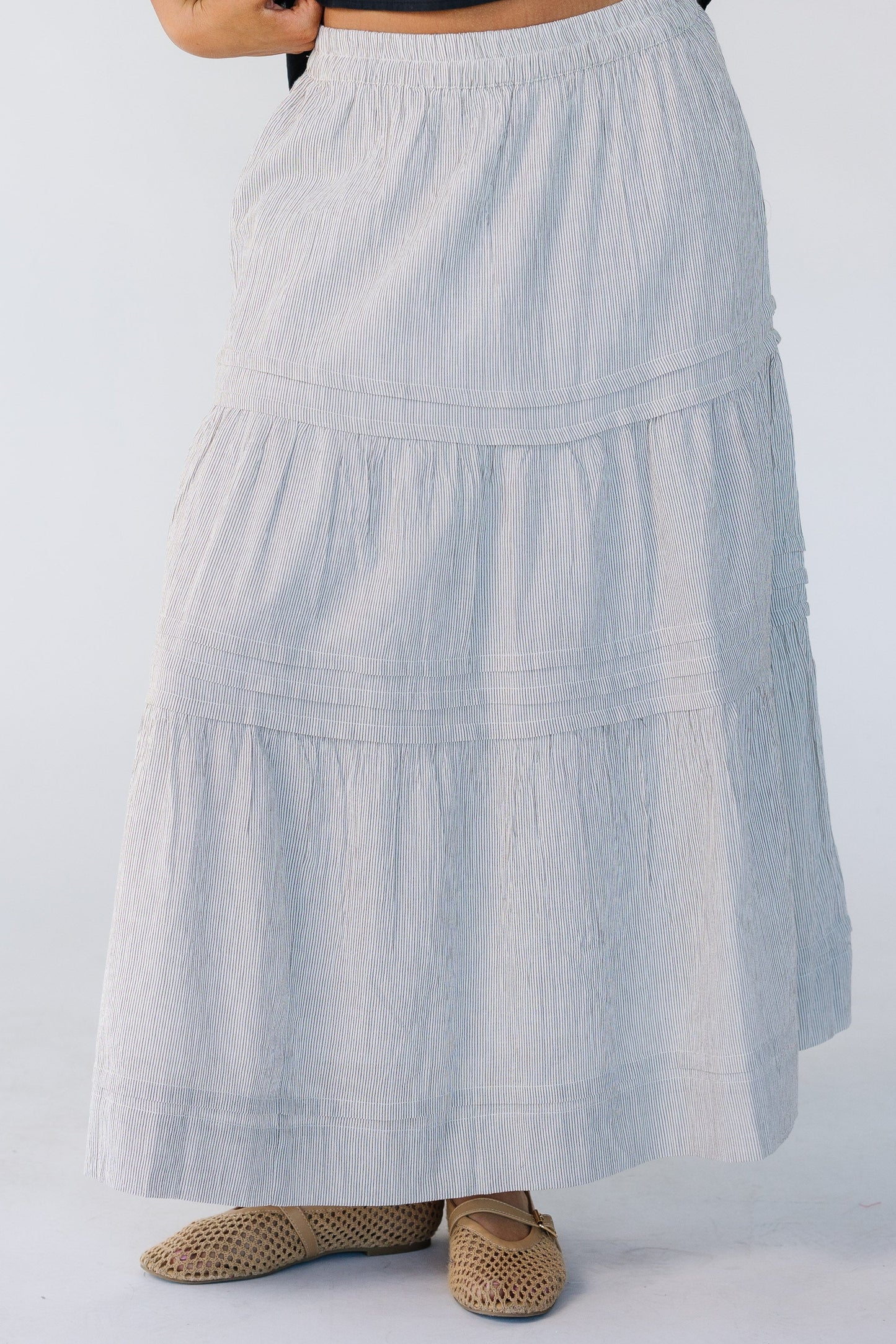 Woman wearing a vertical stripe skirt in brown and white with horizontal.