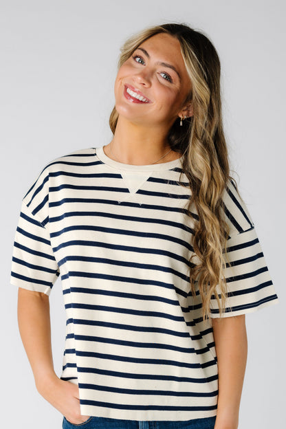 Woman wearing a modest white and black stripe tee with short sleeves.