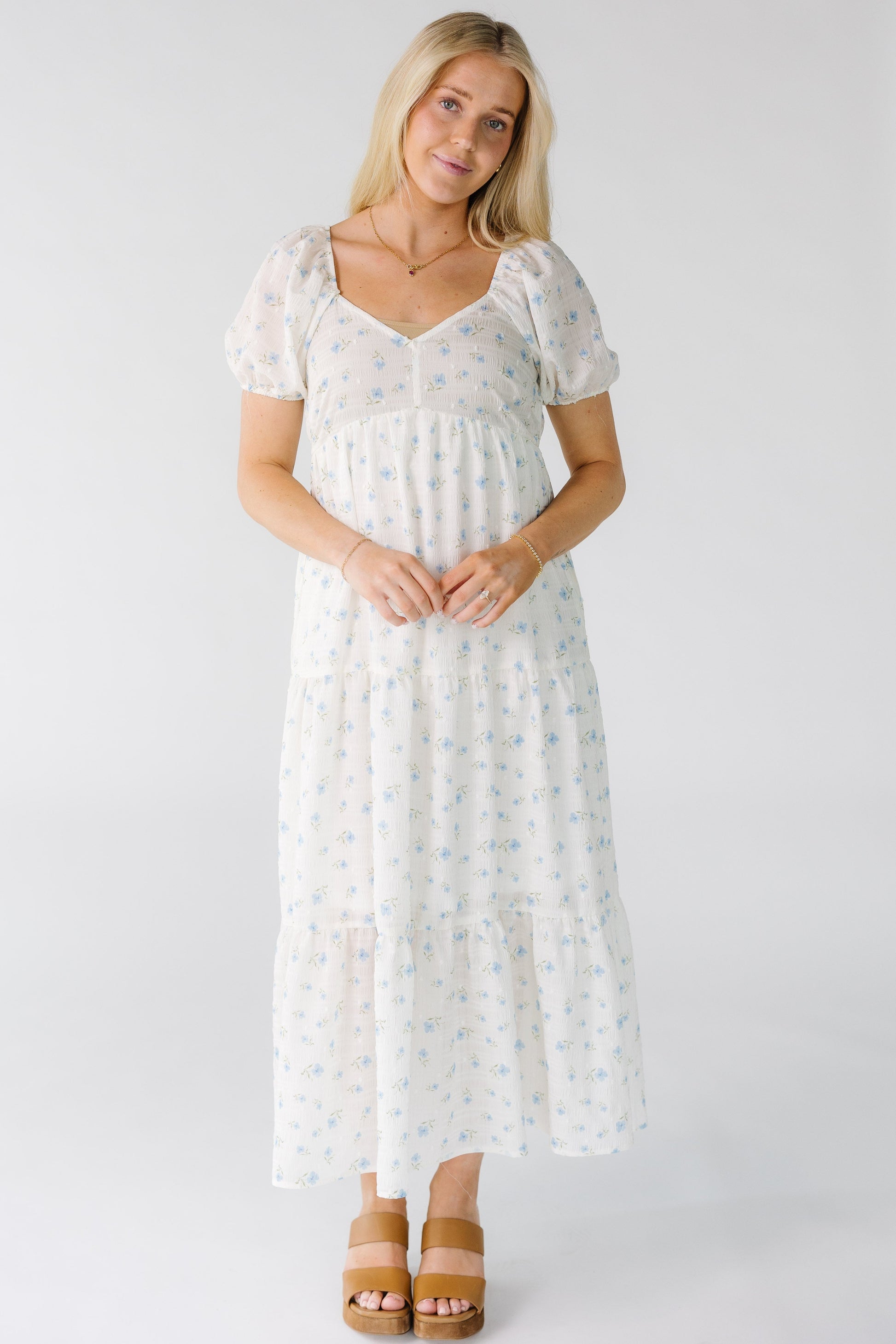 Woman wearing a white floral print midi dress with a sweetheart neckline and multiple gathered tiers.