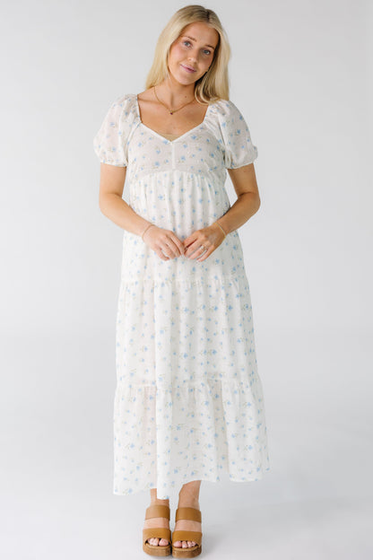 Woman wearing a white floral print midi dress with a sweetheart neckline and multiple gathered tiers.