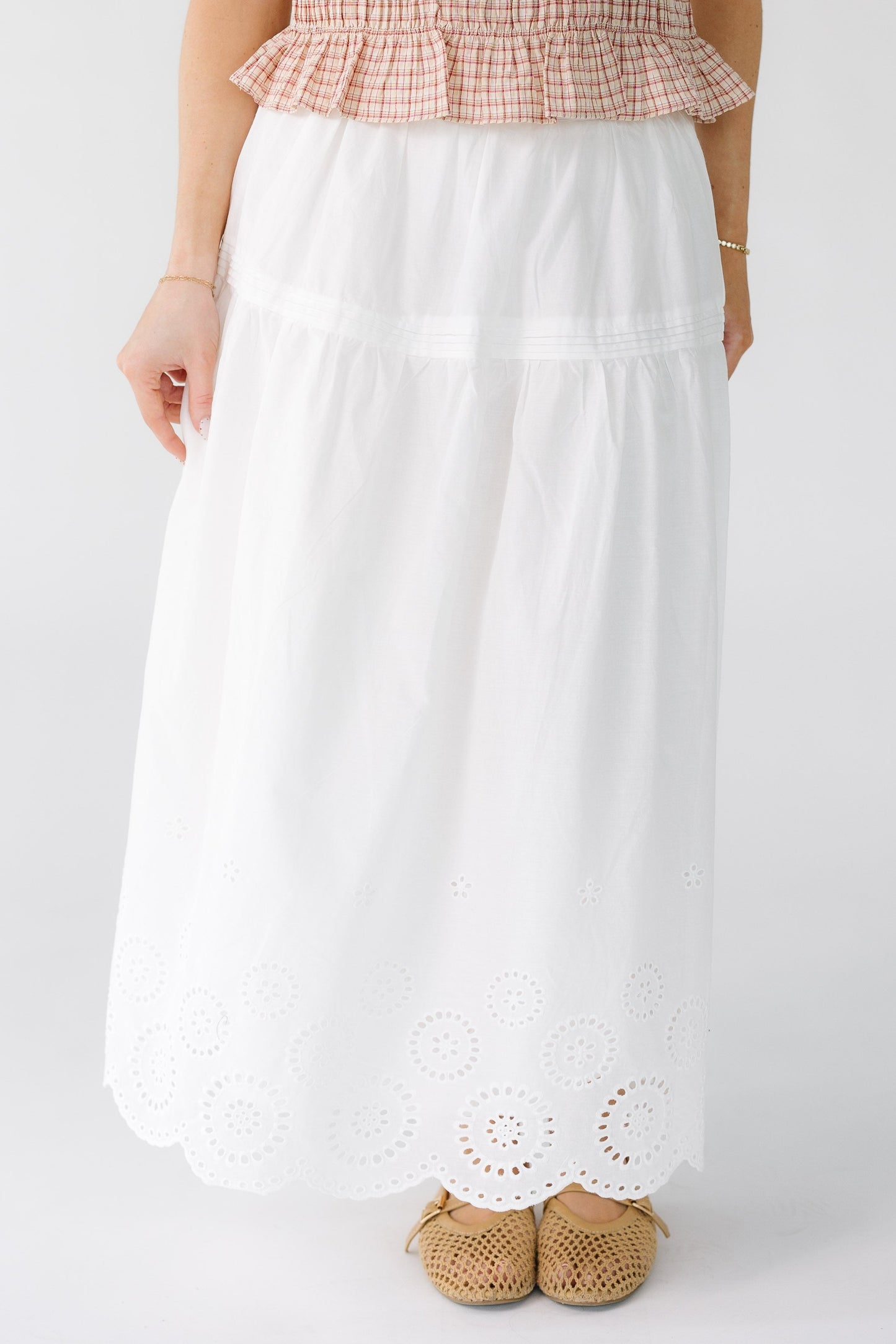 Woman wearing a white midi skirt with an eyelet border pattern.