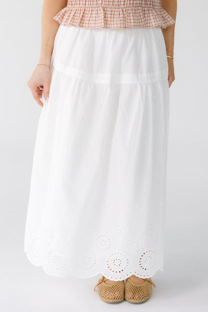 Woman wearing a white midi skirt with an eyelet border pattern.