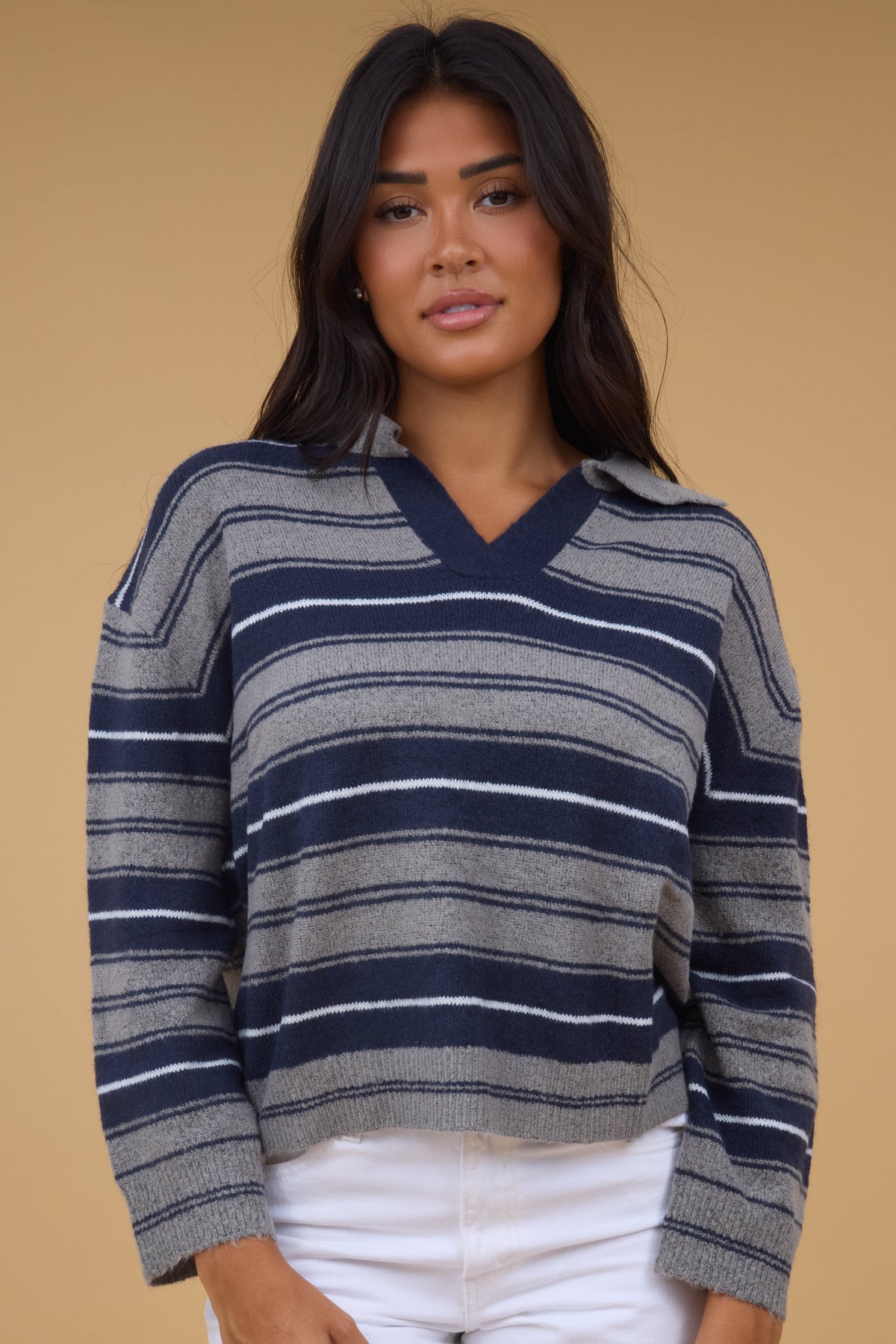 Young woman wearing a grey & navy stripe sweater with a V-neckline, pointed collar and long sleeves.