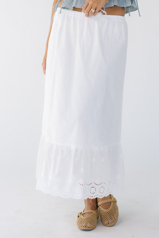 Young woman wearing a modest white midi skirt with a wide bottom eyelet ruffle with a narrow elastic waist.