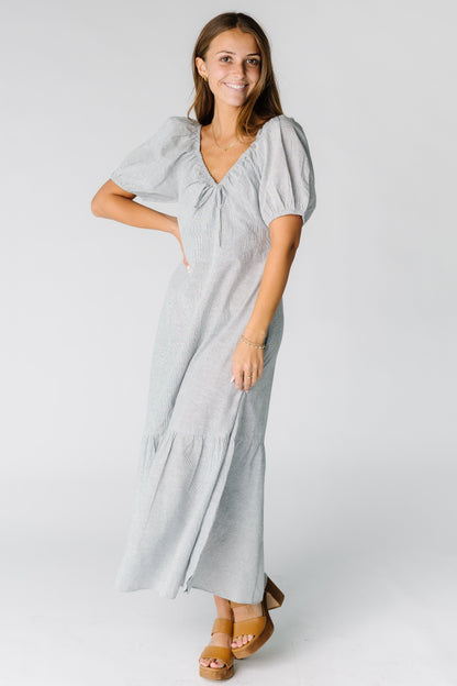 Woman wearing a navy stripe midi-maxi dress with a wide bottom ruffle