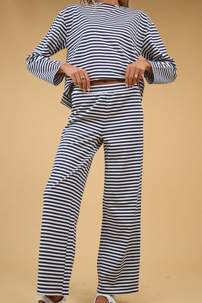 A woman wearing  a 2 piece lounge set in navy & white stripe with long sleeves and an elastic waistband.