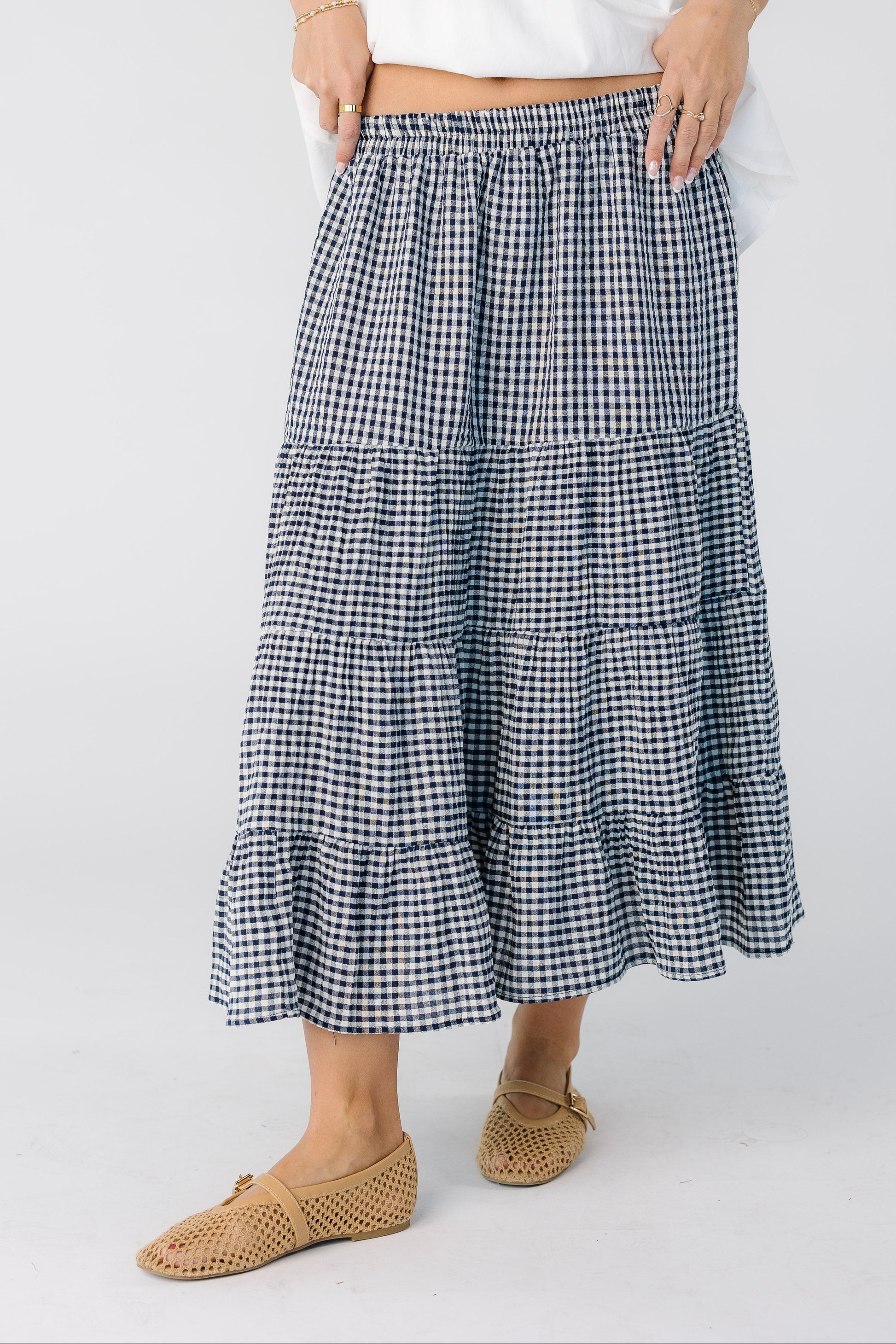 Woman wearing a navy and white gingham midi skirt with tiers and an elastic waistband