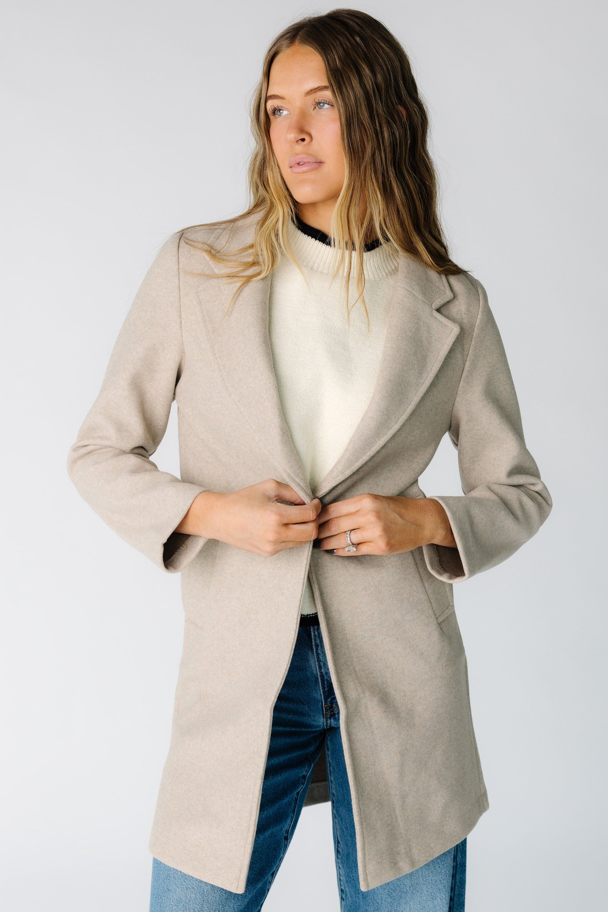 Woman wearing a modest light beige jacket with long sleeves and and mid thigh length