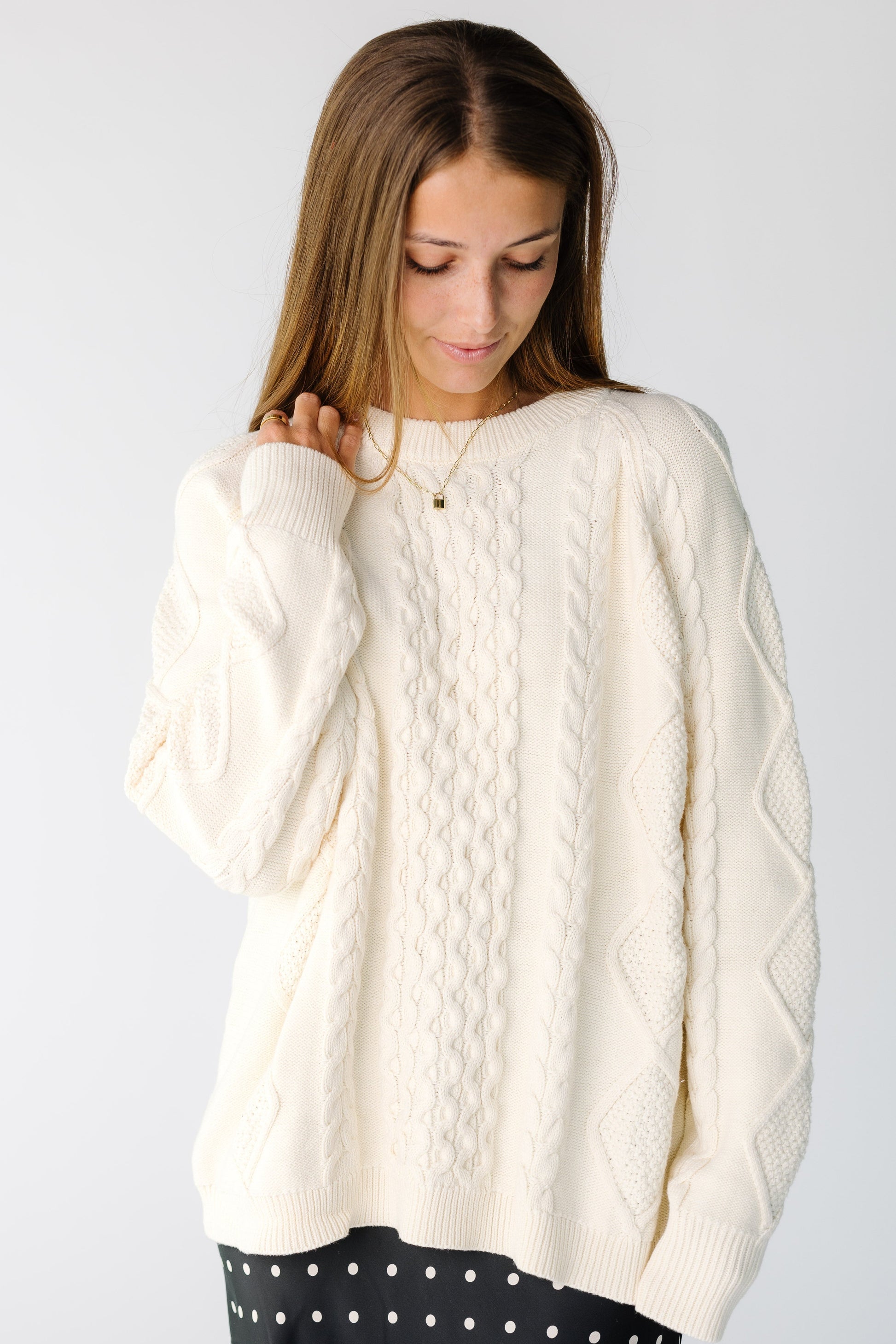 Woman wearing a long sleeve cable knit cardigan in white