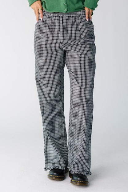 Woman wearing a pair of slightly loose fitting black and white plaid trousers with a ruffle hem