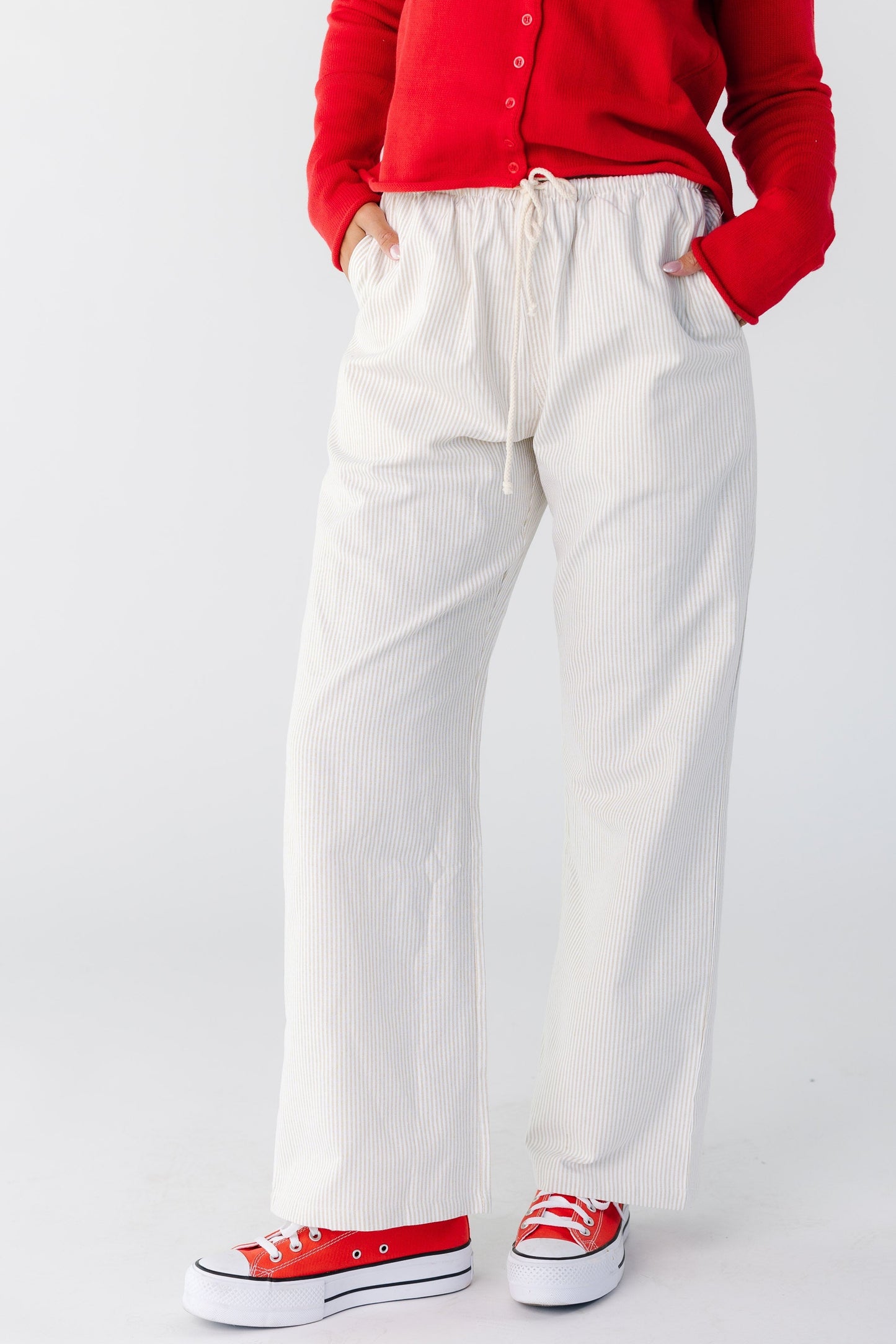 Woman wearing a modest pair of taupe and white stripe pant with side pockets