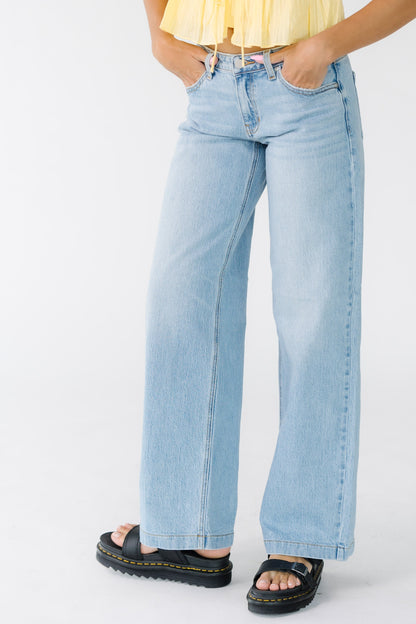 Young woman wearing wide leg pair of jeans in light denim.