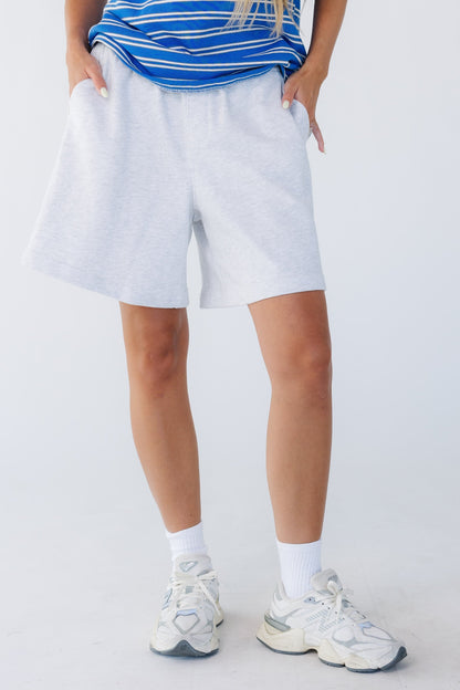 Woman wearing a loose fitting wide leg knit shorts with side pockets and wide elastic waistband.