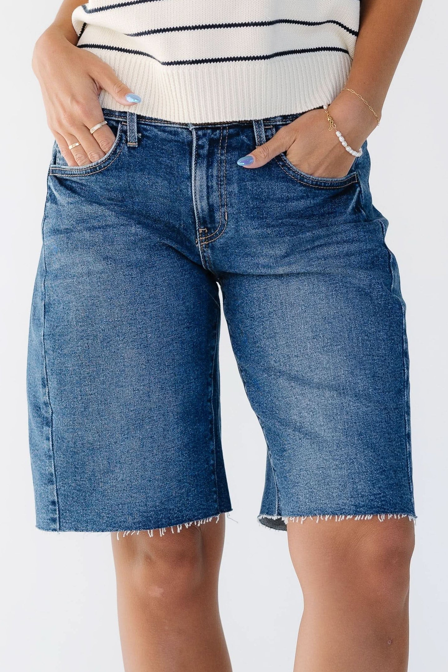 Close up view of a woman wearing a pair of modest dark denim shorts that are knee length.