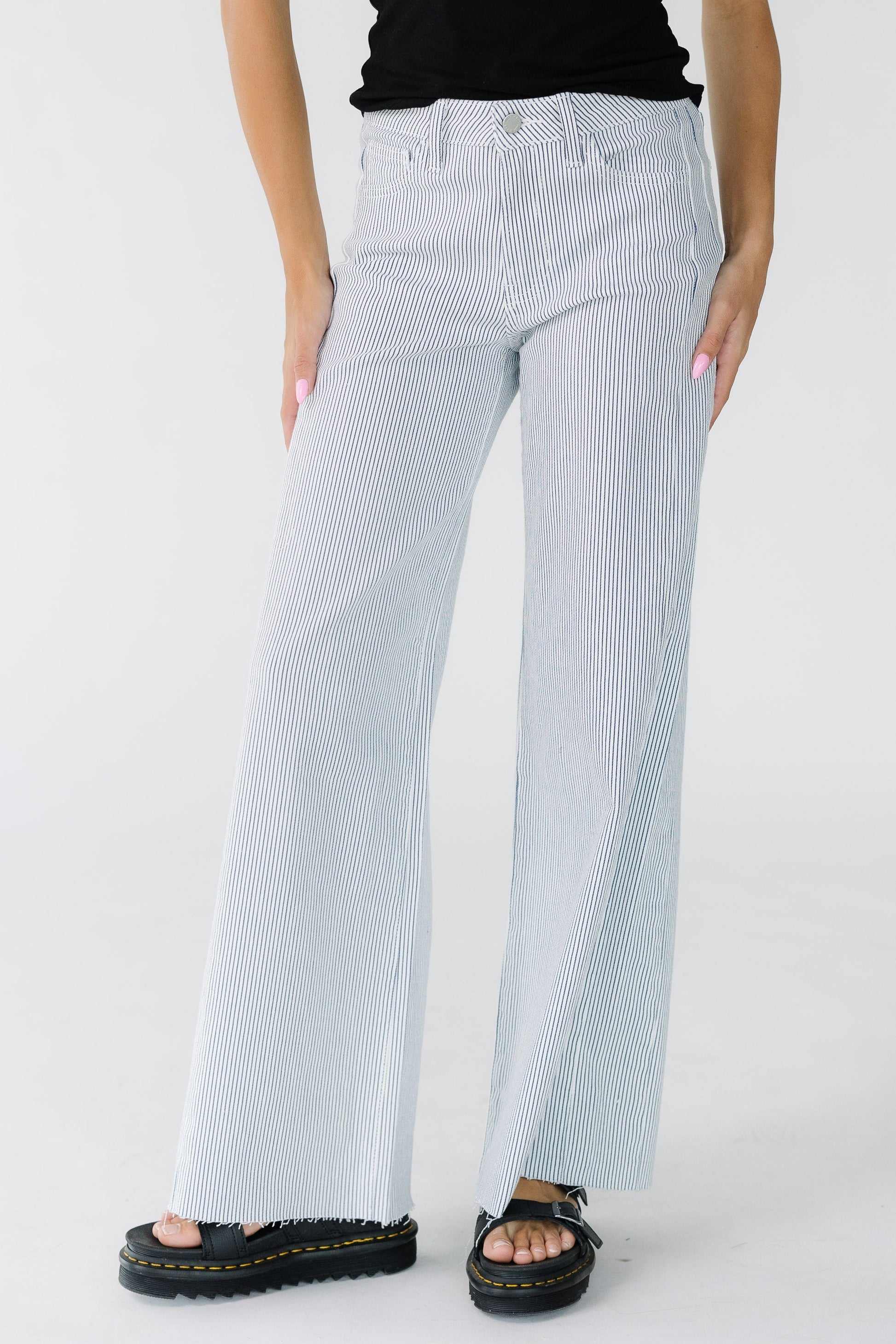 Young woman wearing white wide leg jeans with thin navy stripes and scissor cut hem.