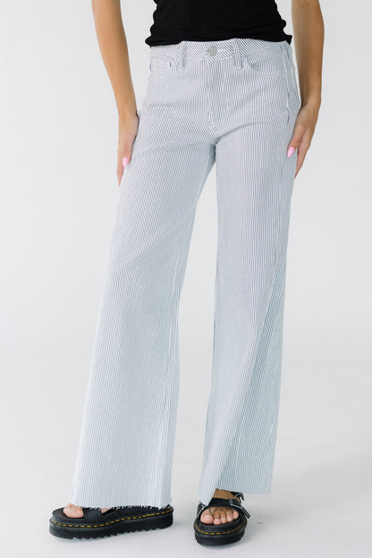 Young woman wearing white wide leg jeans with thin navy stripes and scissor cut hem.