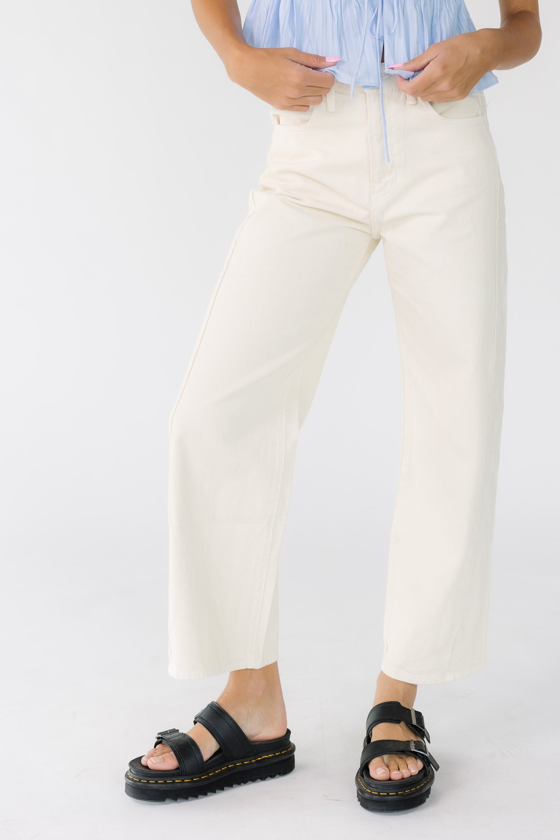 Young woman wearing a pair of off white wide leg pants.