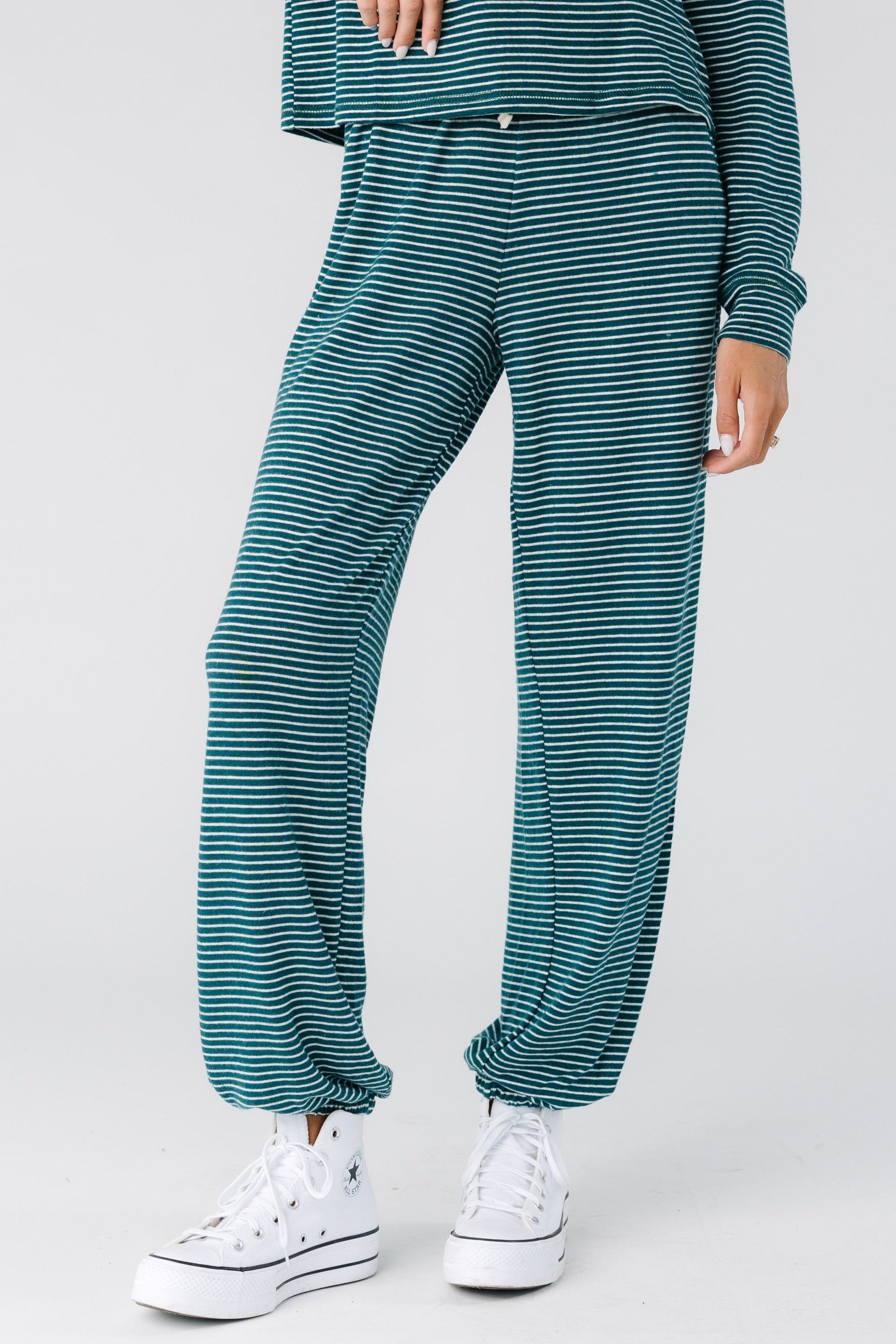 Woman wearing a pair of green stripe lounge pants with elastic cuffs