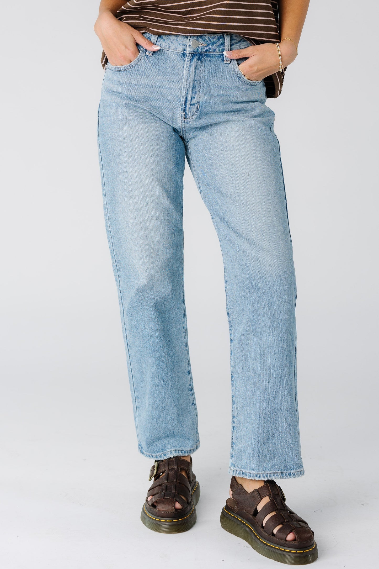 A woman wearing a pair of hemmed  light denim straight cut jeans.