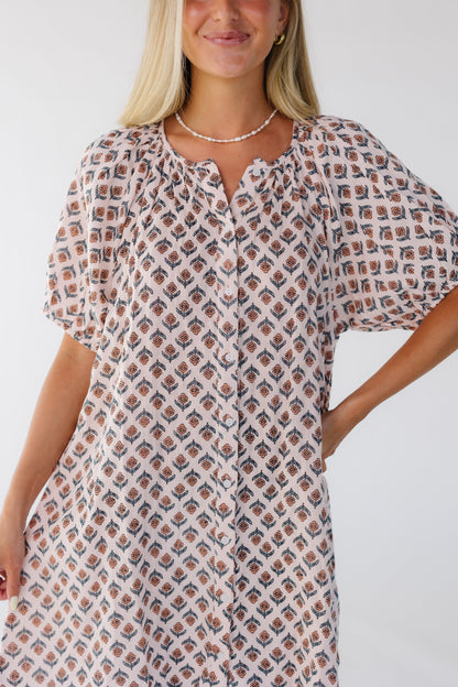 Closer view of a woman wearing a button down pink floral dress cut above the knee.