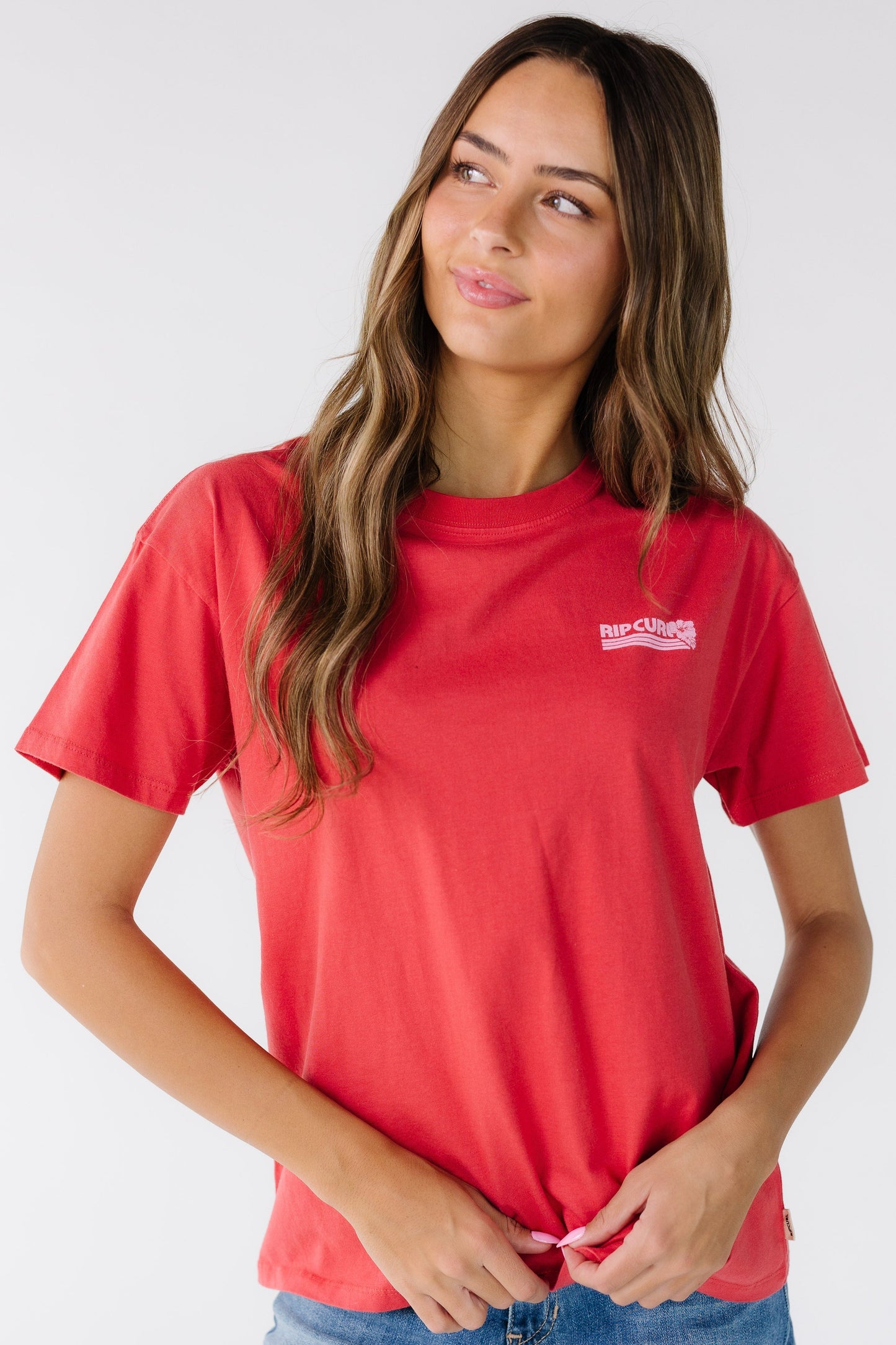 Woman wearing a red graphic tee with a small front Rip Curl graphic tee.