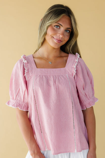 Woman wearing a red & white stripe loose fitting blouse with a square neckline, puff sleeves and lace details.