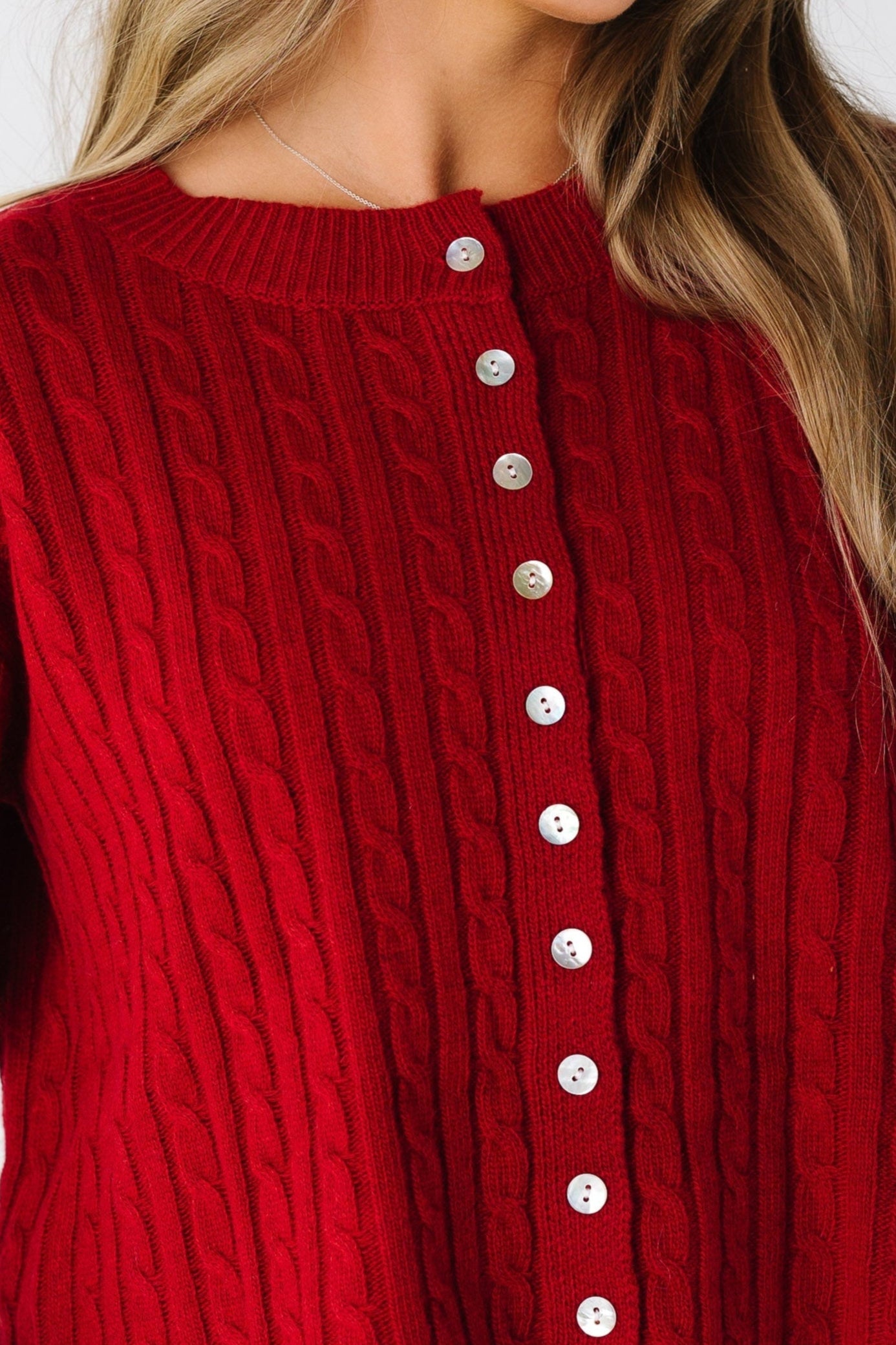 Woman wearing a red cable knit cardigan with short sleeves
