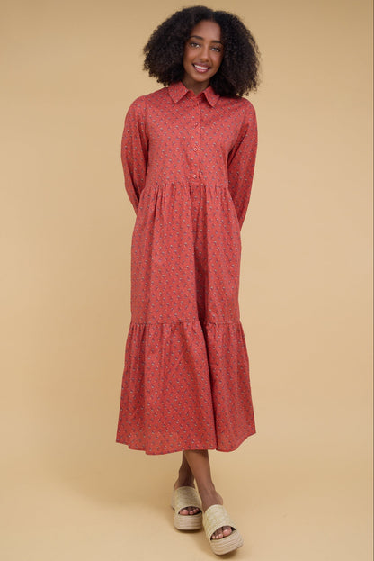 Young woman wearing a modest red midi dress with a pointed collar, button down bodice, long sleeves and a full gathered skirt.