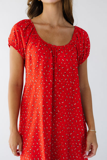 Closer view of a woman wearing a red floral loose fitting dress with a scoop neckline and short puff sleeves.