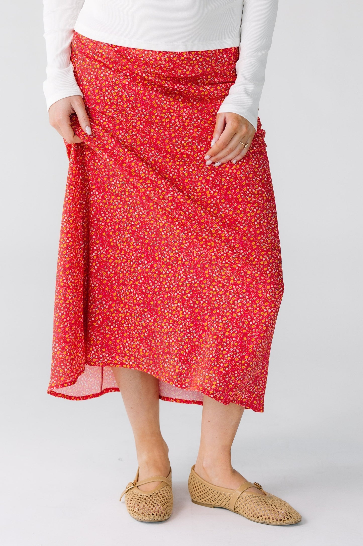 Woman wearing a red floral midi skirt in an A-line style.