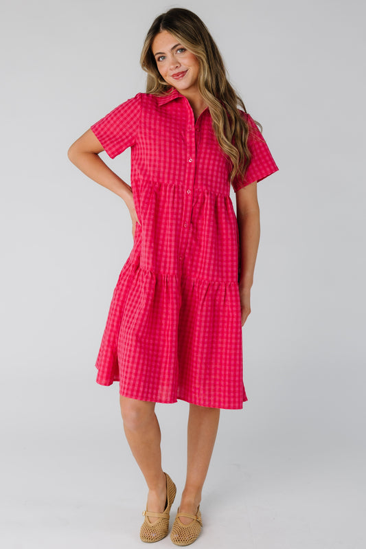 Woman wearing a red and pink gingham button down dress with short sleeves.