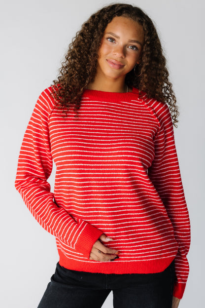 Woman wearing a red and white stripe sweater with long raglan and exposed seams