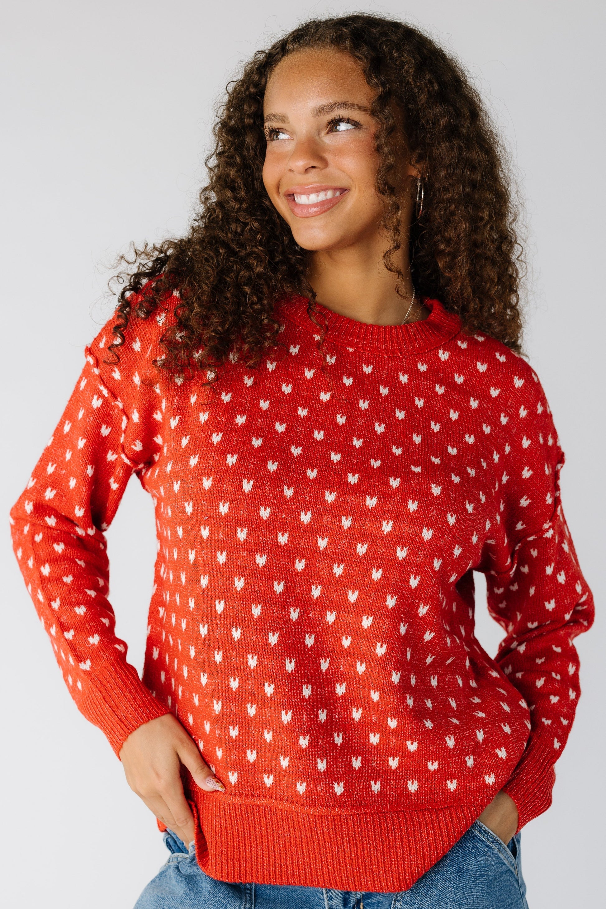 Woman wearing a red pullover with white hearts and long sleeves