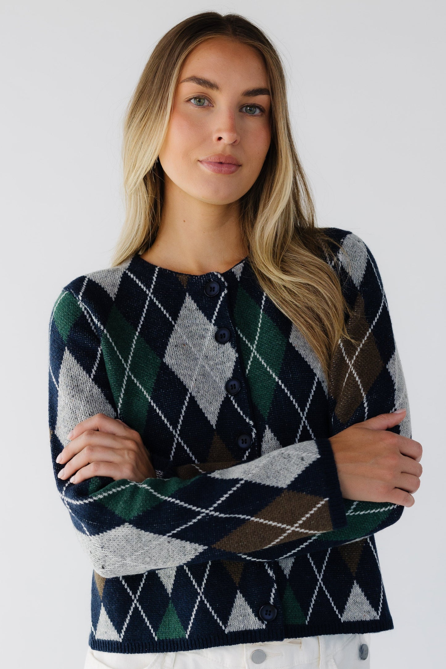 Woman wearing a loose fitting navy argyle cardigan with a round neckline and long sleeves.