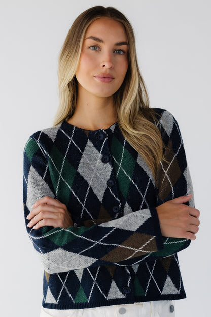 Woman wearing a loose fitting navy argyle cardigan with a round neckline and long sleeves.