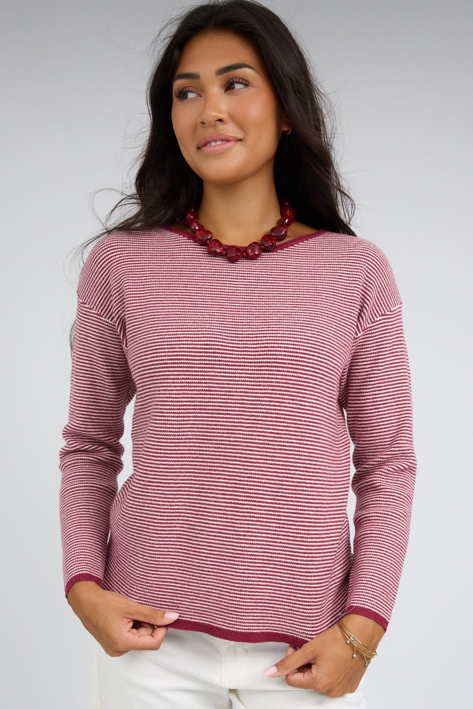 Woman wearing a burgundy and white stripe long sleeve waffle textured top.