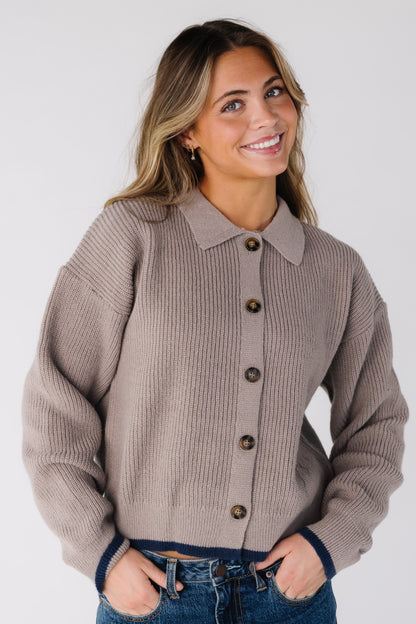 Woman wearing a taupe button cardigan with long sleeves and pointed collar