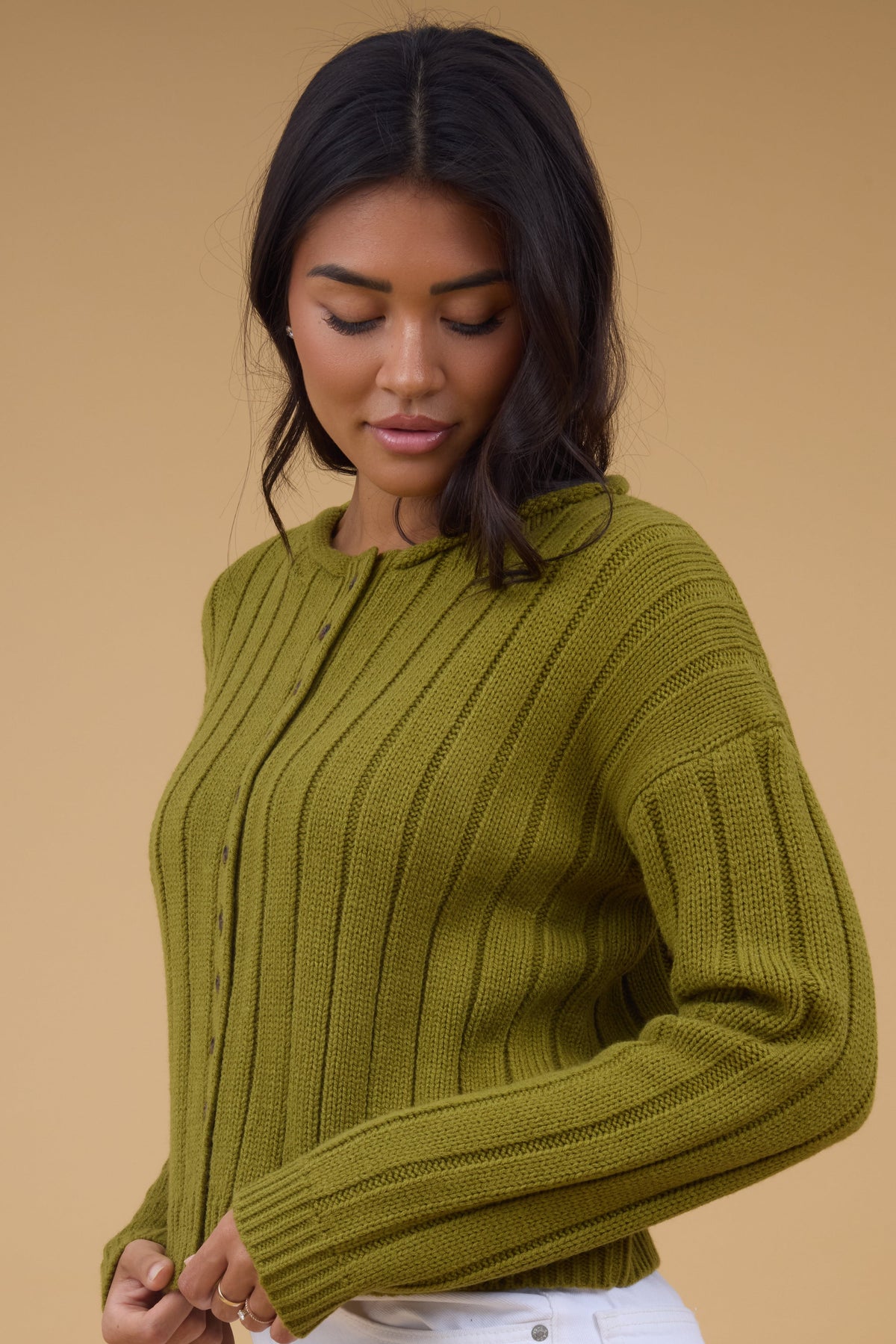 A side view of a woman wearing an olive wide ribbed cardigan with long sleeves.