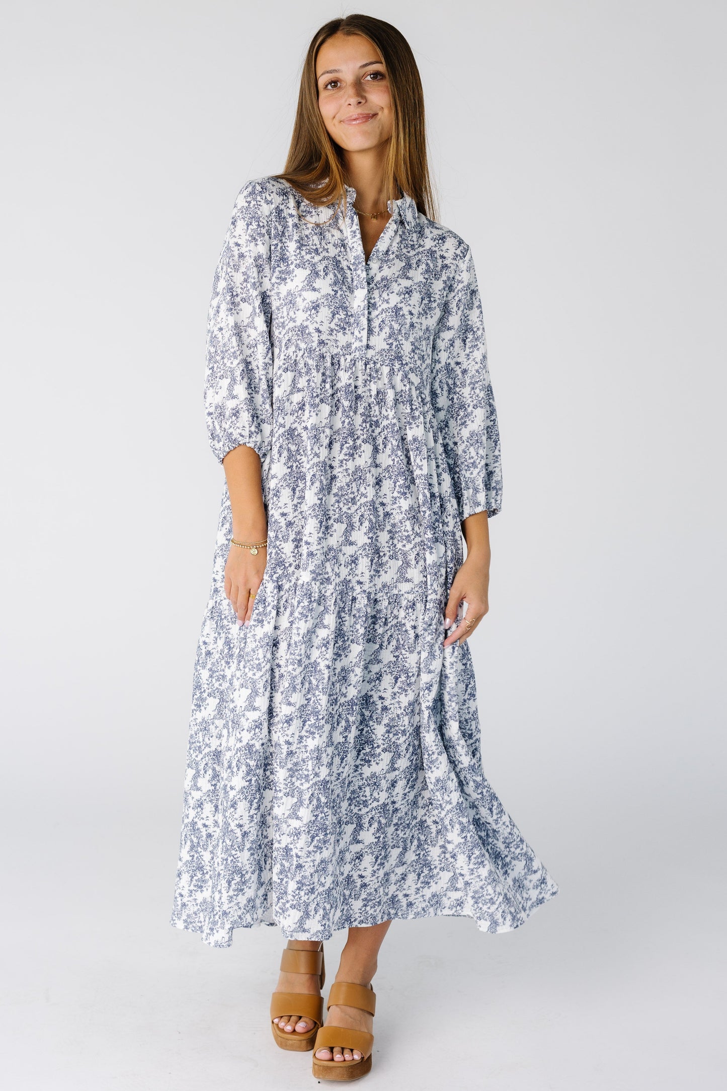Woman wearing a loose and flowing blue print midi dress with tiered skirt