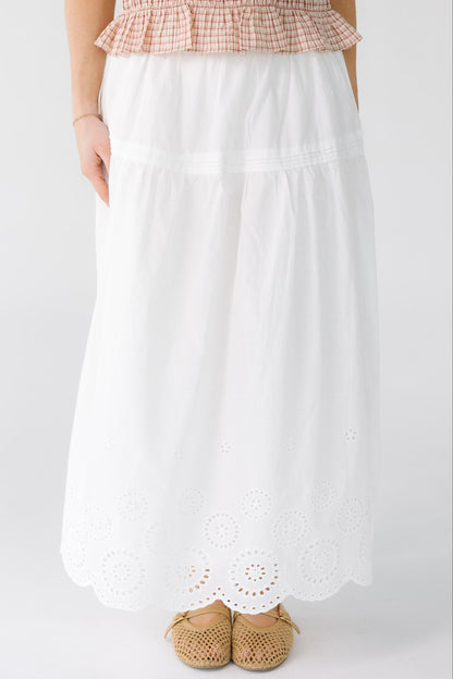 Woman wearing a white midi-maxi skirt with a drop waist and an eyelet bottom border pattern.