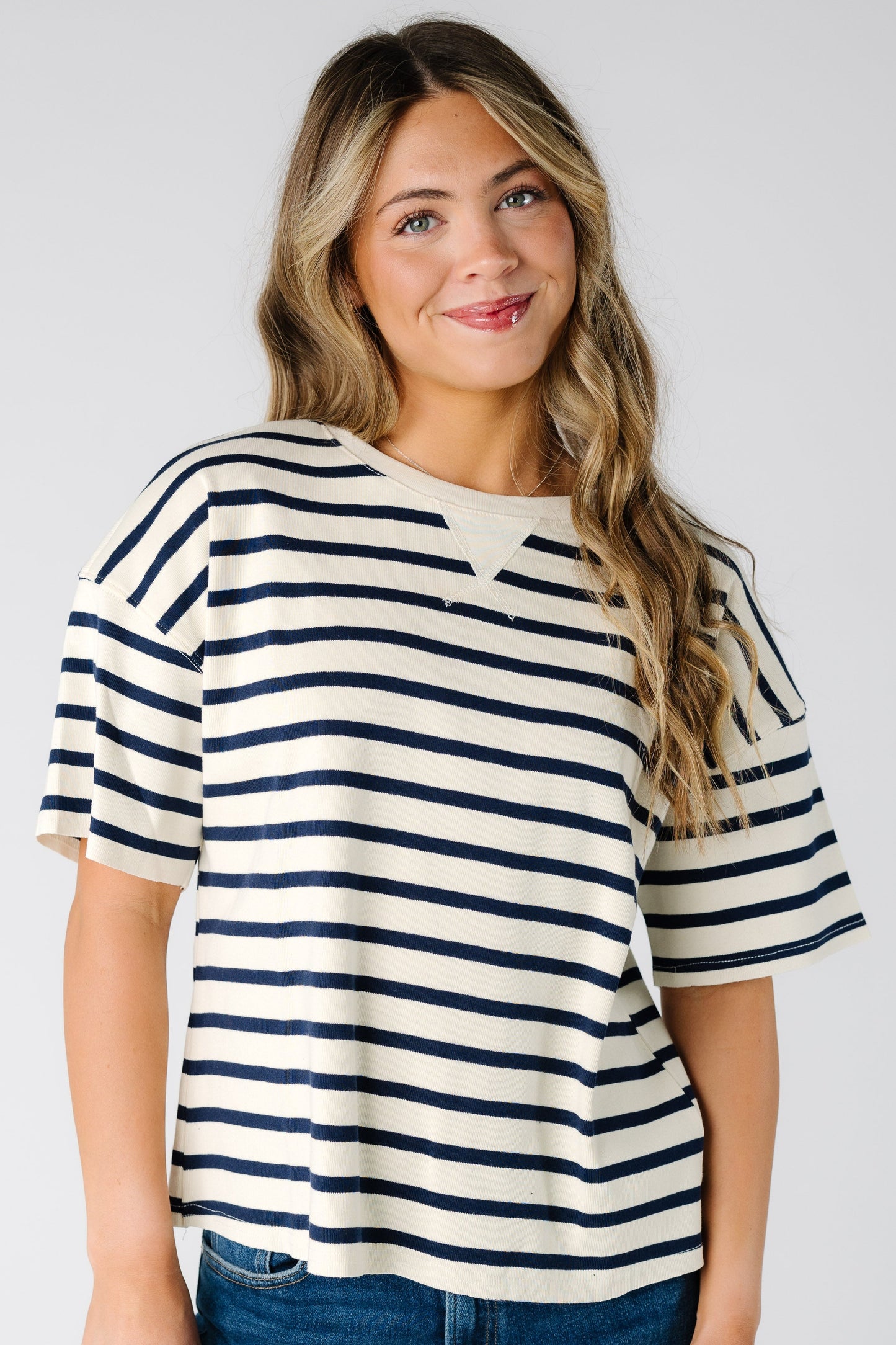 Woman wearing a white short sleeve tee with narrow black stripe.