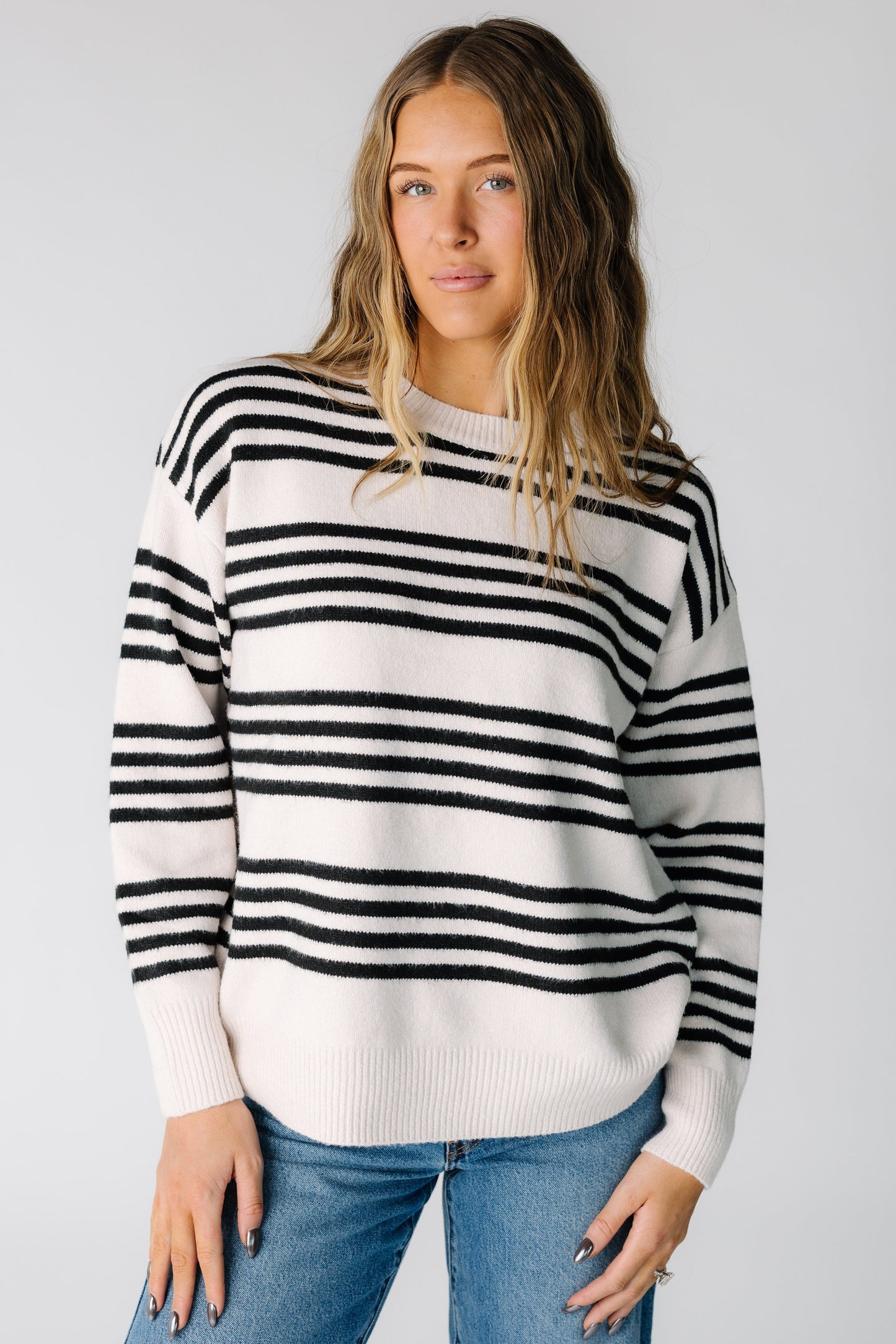 Woman wearing a light beige pullover sweater with black stripe in groups of 4