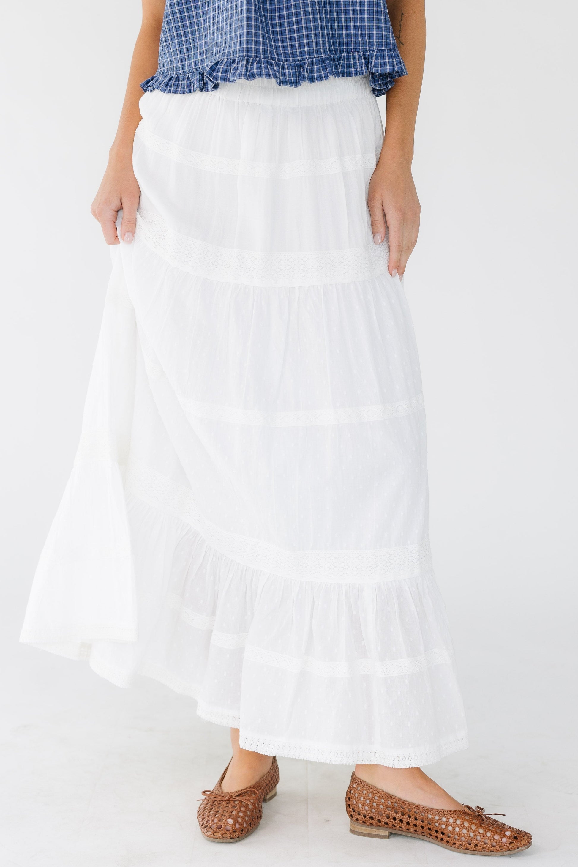 Young woman wearing a modest white tiered skirt with multiple rows of lace.