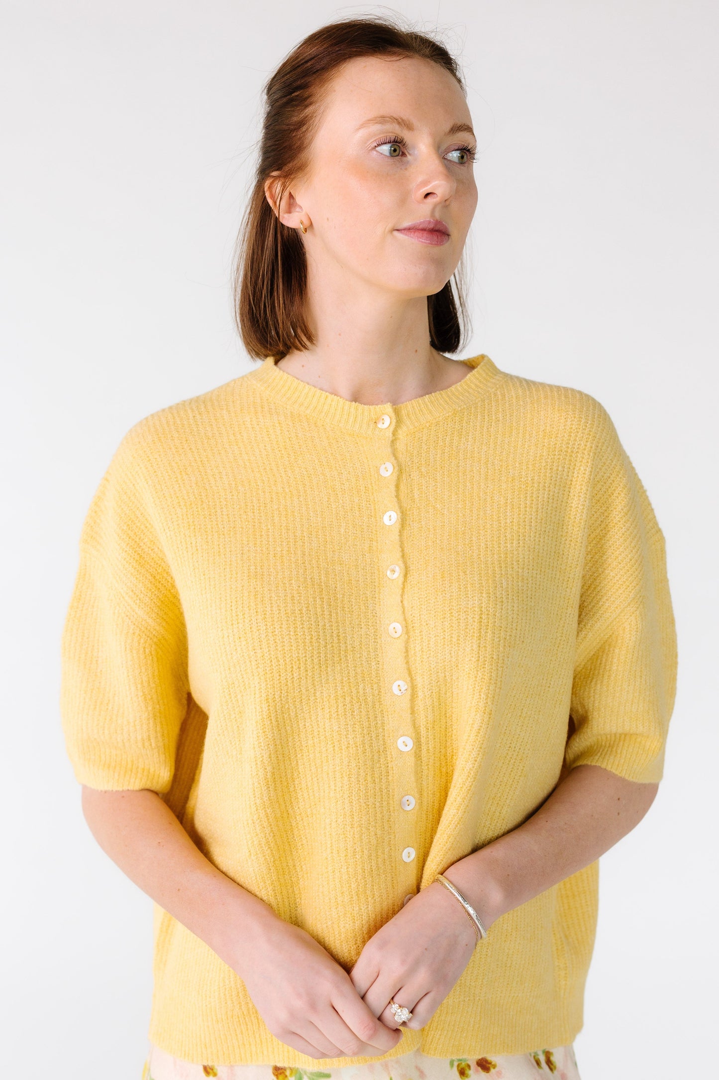 Young woman wearing a yellow button down cardigan with short sleeves.