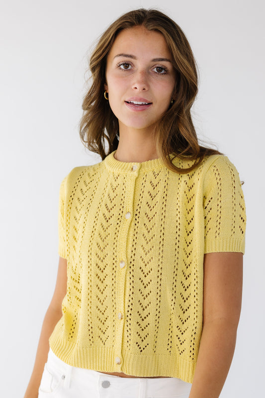 Young woman wearing a modest, lacey knit, button down cardigan with short sleeves and a crew neckline.