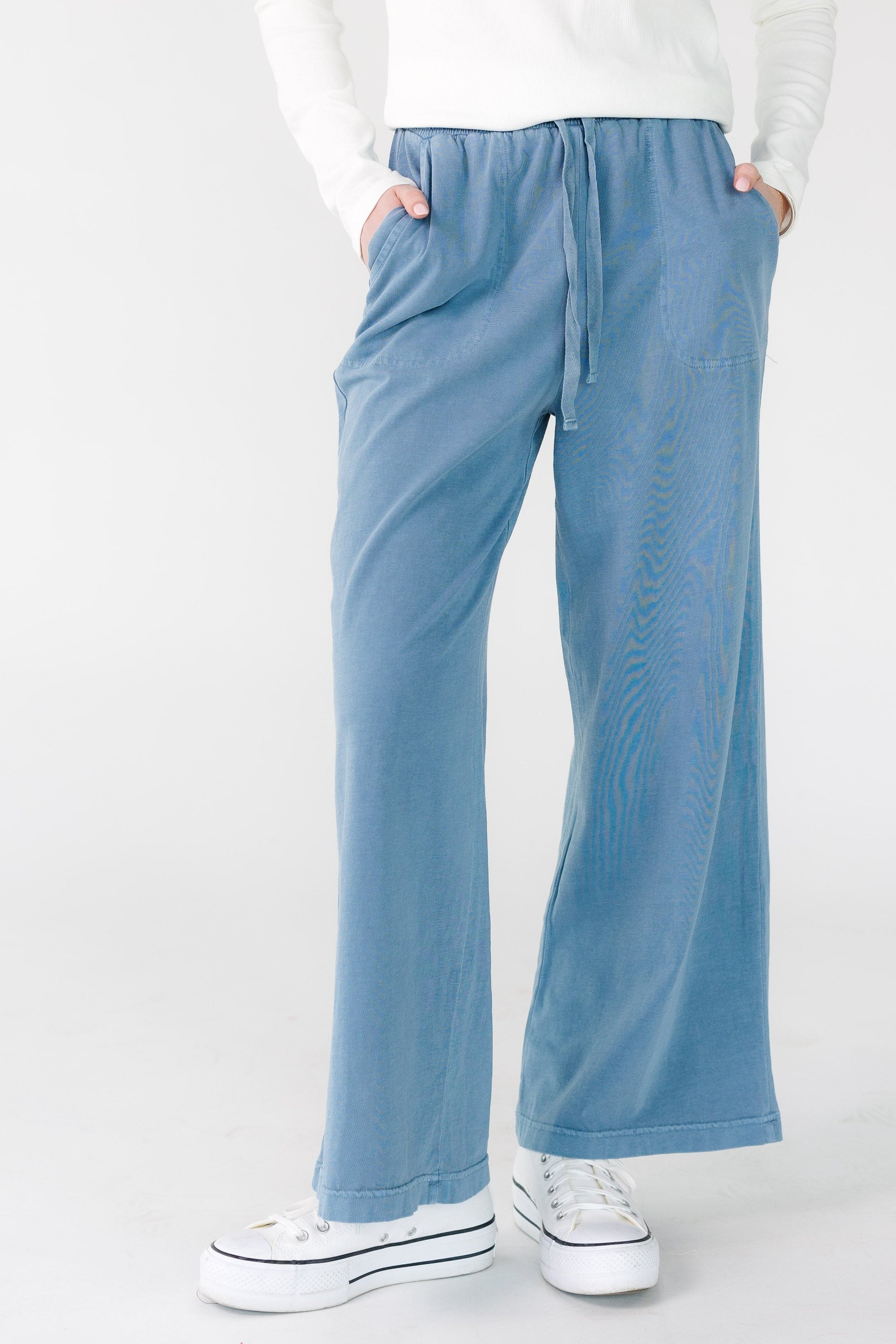 Young woman wearing blue wide legs pants with pockets.