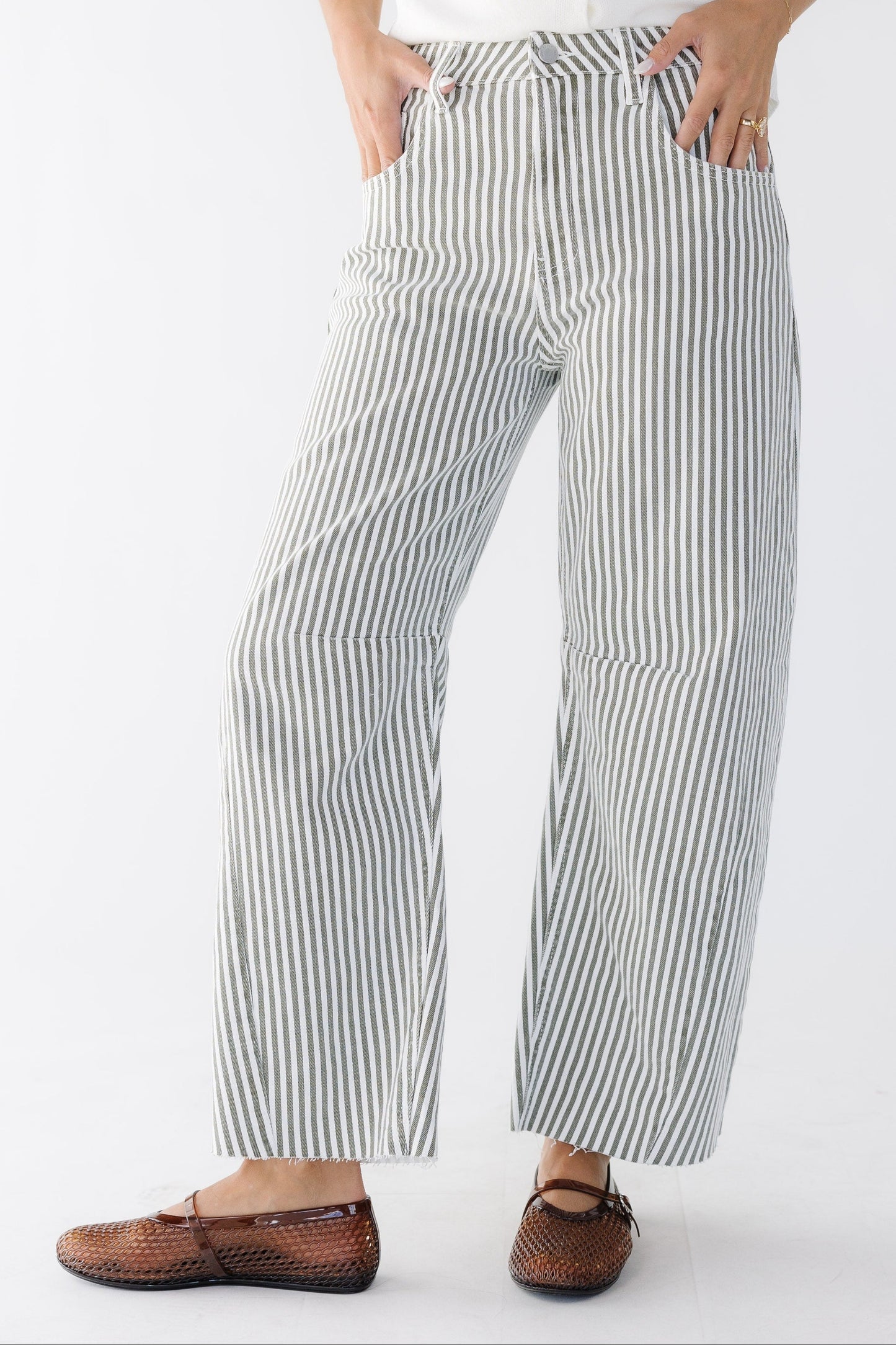 Young woman wearing  wide cut, barrel jeans in white and olive stripe with pockets.